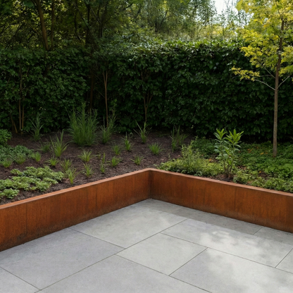 Lage border van cortenstaal langs een modern betegeld terras met diverse vaste planten en een groene haag.