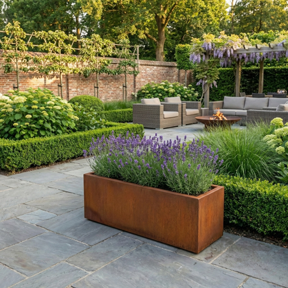 Lage rechthoekige Cortenstalen plantenbak met paarse lavendel op een modern terras met een loungehoek.