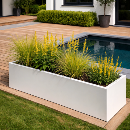 Strakke rechthoekige witte plantenbak gevuld met levendige gele bloemen en siergrassen op een houten vlonder in een moderne tuin met zwembad.